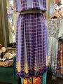 Blue plaid dress with gold embroidery on a mannequin in a store setting.