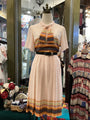 Mannequin wearing a patterned dress with a colorful top in a store setting