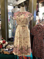 Floral dress on a mannequin in a store setting with other clothing items.