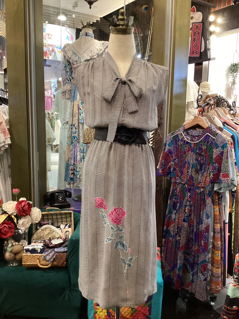 Mannequin wearing a gray dress with floral embroidery in a store setting