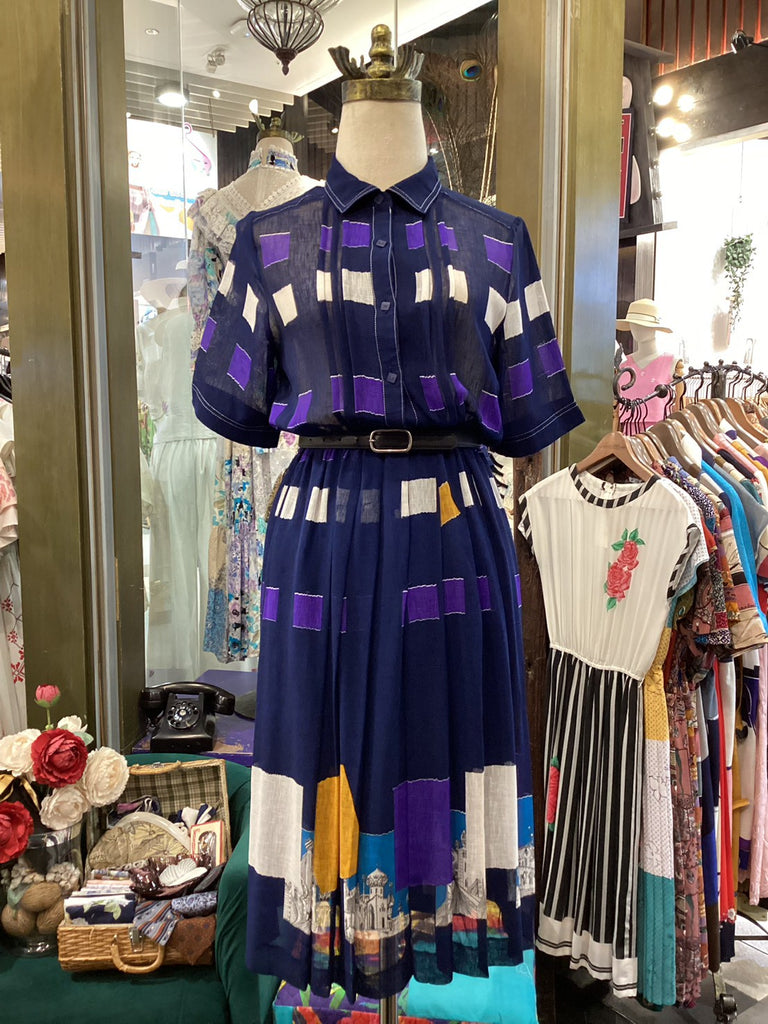 Mannequin wearing a colorful dress with a patterned background of clothing and decor.