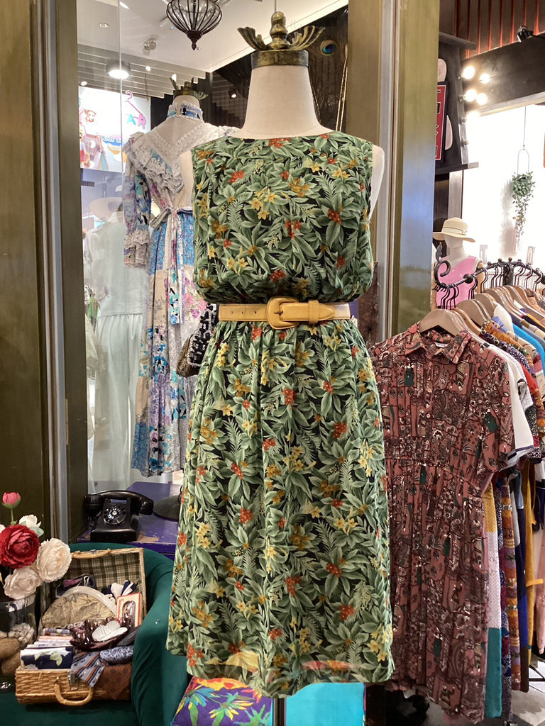 Mannequin wearing a green floral dress in a clothing store setting