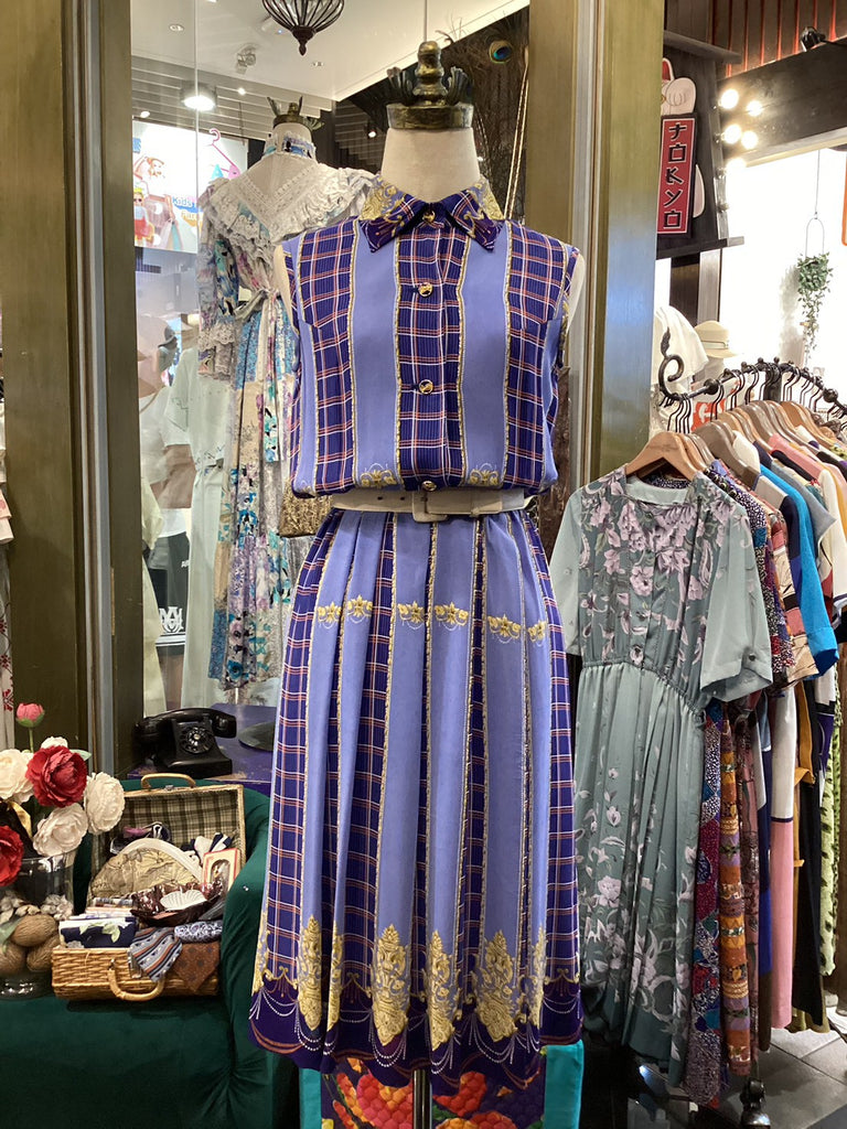 Mannequin wearing a vintage-style outfit with a plaid top and striped skirt in a store setting.