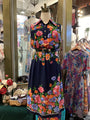 Floral dress on a mannequin in a store setting with other dresses.