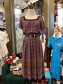 Mannequin wearing a patterned dress in a store setting with other clothing items.