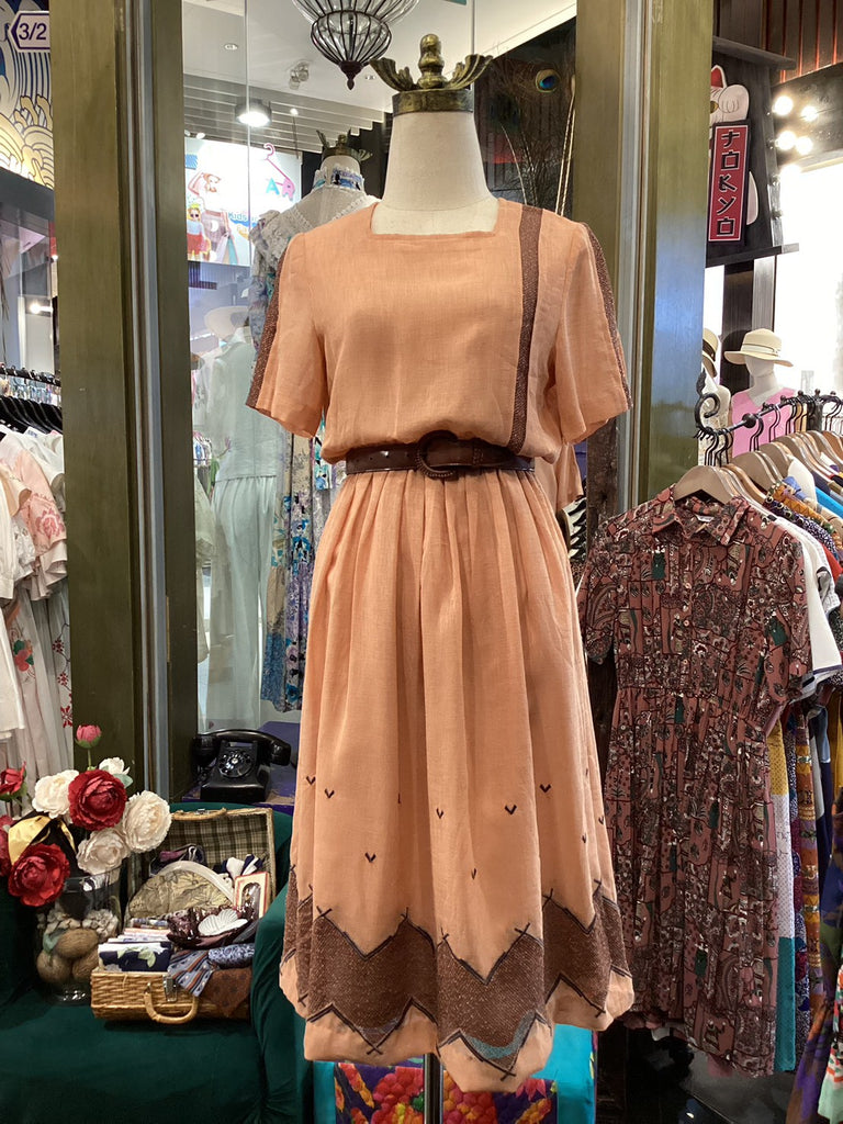 Vintage dress on a mannequin in a store setting with other clothing items.