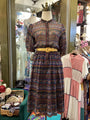 Patterned dress on a mannequin in a store setting with other clothing items.