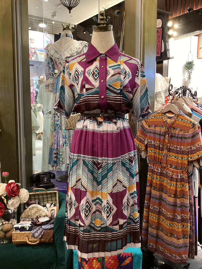 Colorful patterned dress on a mannequin in a store setting with other clothing items.