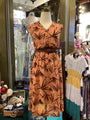 Brown dress with leaf pattern on a mannequin in a store setting