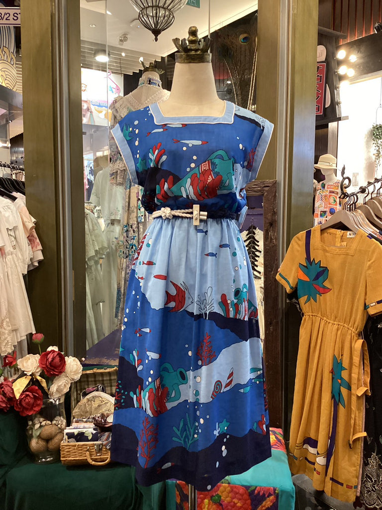 Colorful dress with underwater design on a mannequin in a store setting.