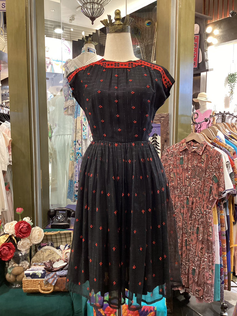 Black dress with red patterns on a mannequin in a store setting