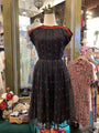 Black dress with red patterns on a mannequin in a store setting