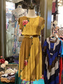 Yellow dress with floral embroidery on a mannequin in a store setting.