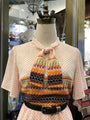 Mannequin wearing a patterned blouse with a colorful design in a store setting