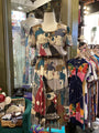Colorful dress on a mannequin in a store setting with various clothing items around.