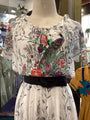 Floral and peacock patterned blouse on a mannequin in a store setting.