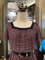 Mannequin wearing a patterned top with a decorative belt in a store setting