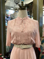 Pink lace dress on a mannequin with a blurred store interior background