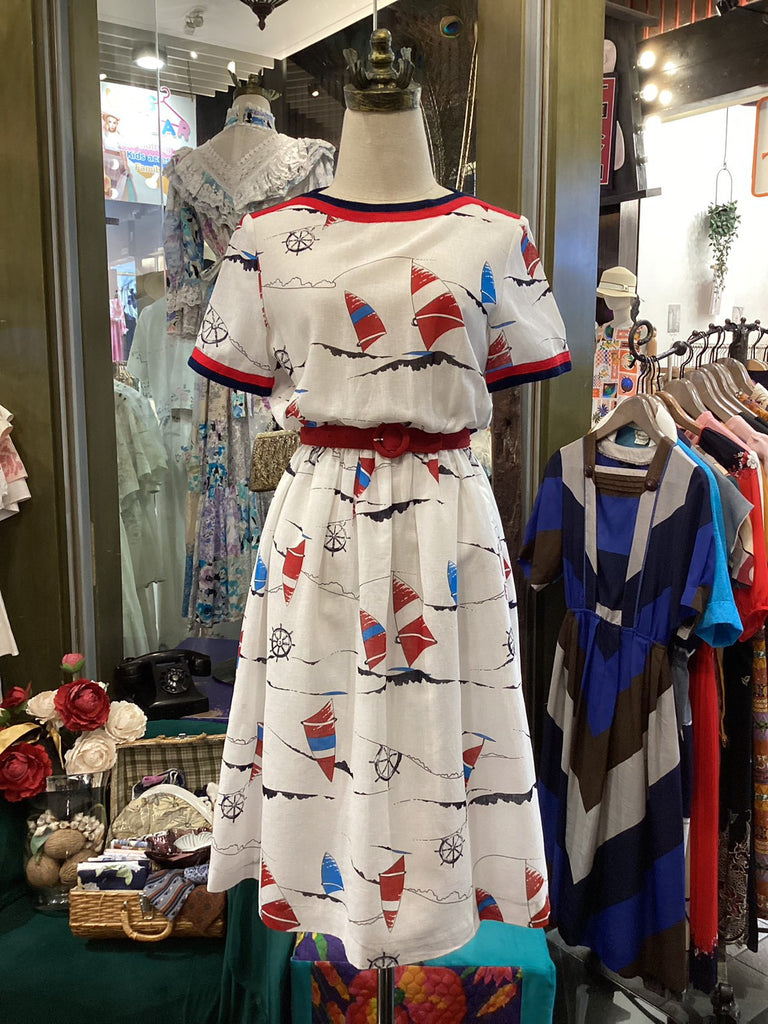 Mannequin wearing a white dress with red and blue accents in a clothing store.