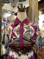 Mannequin wearing a colorful patterned shirt with a purple collar in a store setting.