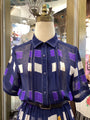 Navy blue dress with purple and white geometric pattern on a mannequin in a store setting.