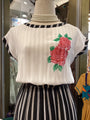 Mannequin wearing a white blouse with floral design and black and white striped skirt.