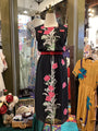 Black dress with floral embroidery on a mannequin in a store setting.