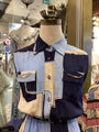 Mannequin wearing a patchwork jacket with denim, beige, and navy colors in a store setting.