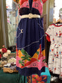 Navy dress with colorful patterns and a belt, displayed in a store setting.