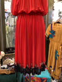 Red pleated dress on a mannequin with a yellow dress in the background.