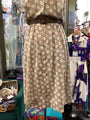 Beige dress with white floral pattern on a mannequin in a store setting.