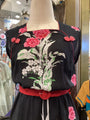 Black dress with floral embroidery on a mannequin in a store setting