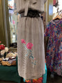 Long dress with floral embroidery on a mannequin in a store setting.