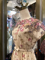 Mannequin wearing a floral dress with a crown in a store setting