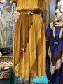 Yellow pleated skirt with floral details worn by a mannequin in a clothing store setting.