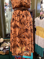 Brown dress with leaf pattern on a hanger in a store setting