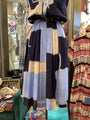 Colorful patchwork dress on a mannequin in a store setting with other clothing items.