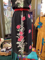 Black dress with floral embroidery on a mannequin against a colorful background