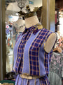 Mannequin wearing a blue plaid outfit with a decorative headpiece in a store setting.