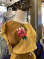 Yellow blouse with floral embroidery on a mannequin in a store setting