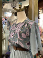 Mannequin wearing a floral blouse with a light-colored jacket in a store setting