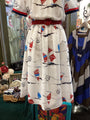 White dress with red belt and sailboat pattern in a store setting