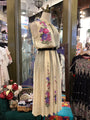 Mannequin wearing a floral embroidered dress in a store setting with other clothing items.