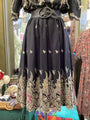 Black embroidered dress on a mannequin with a colorful background