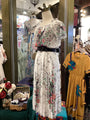 Floral dress on a mannequin with a yellow dress in the background in a store setting.