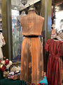 Mannequin wearing a long, patterned dress in a store setting with other clothing items.