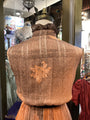 Mannequin wearing a textured brown jacket with a floral design in a store setting