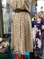 Beige dress with white floral pattern on a mannequin in a store setting.