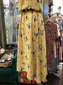 Yellow dress with colorful pattern on a mannequin in a clothing store.