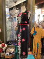 Black dress with pink floral embroidery on a mannequin in a store setting.